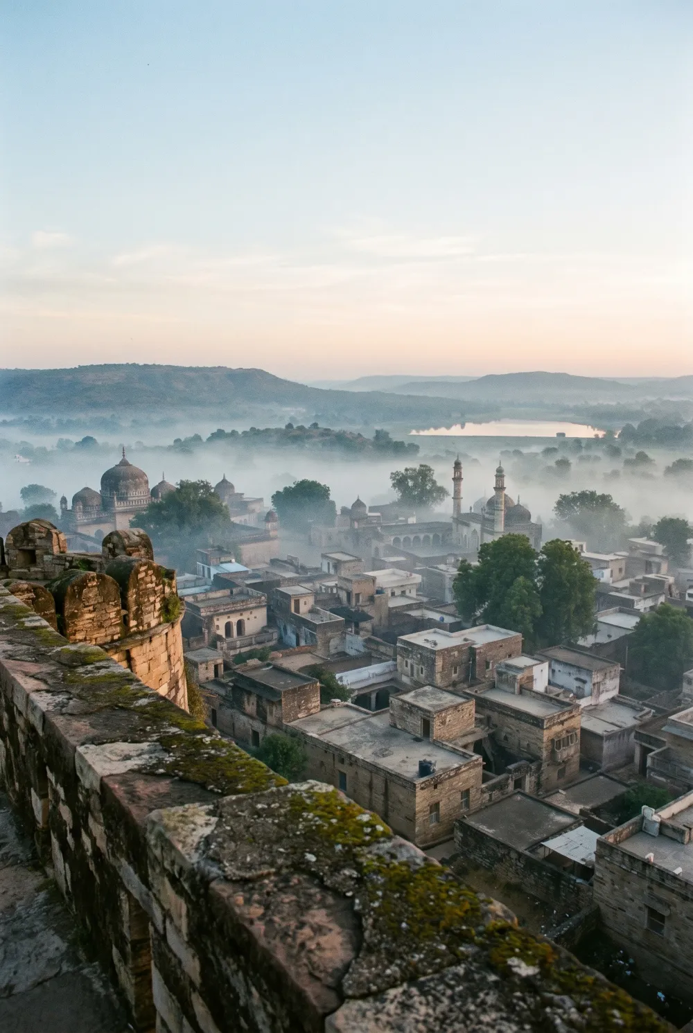 Chanderi's rooftops and fort in the early morning mist